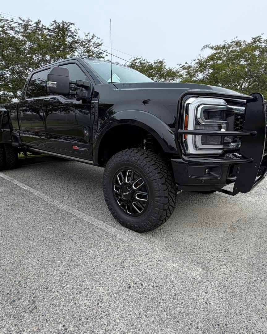 Black lifted Super Duty pickup with off-road tires and a front grille guard